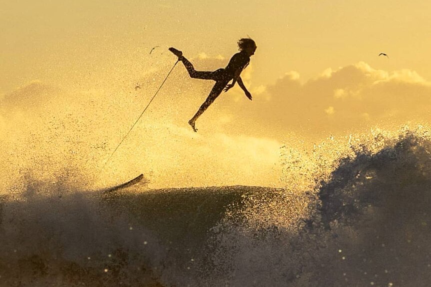 An airborne surfer above the waves.
