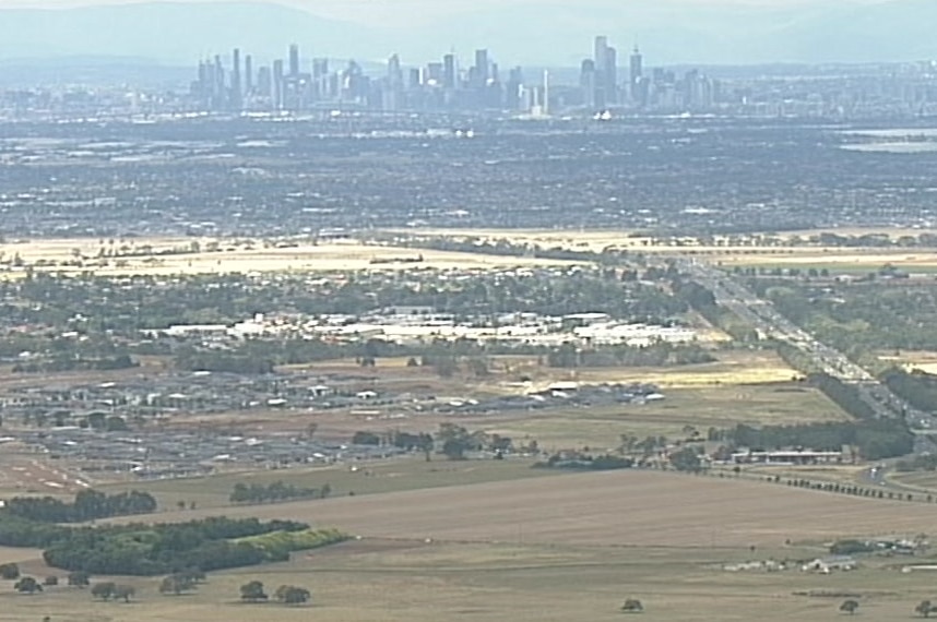 Melbourne skyline in the distance and urban sprawl and undeveloped land in the foreground.