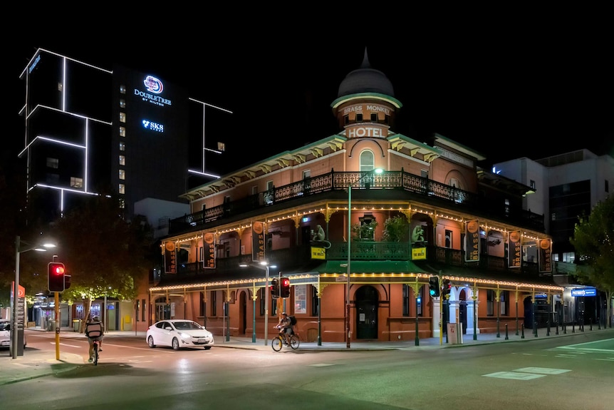 A lit up intersection at night with two cyclists and one car