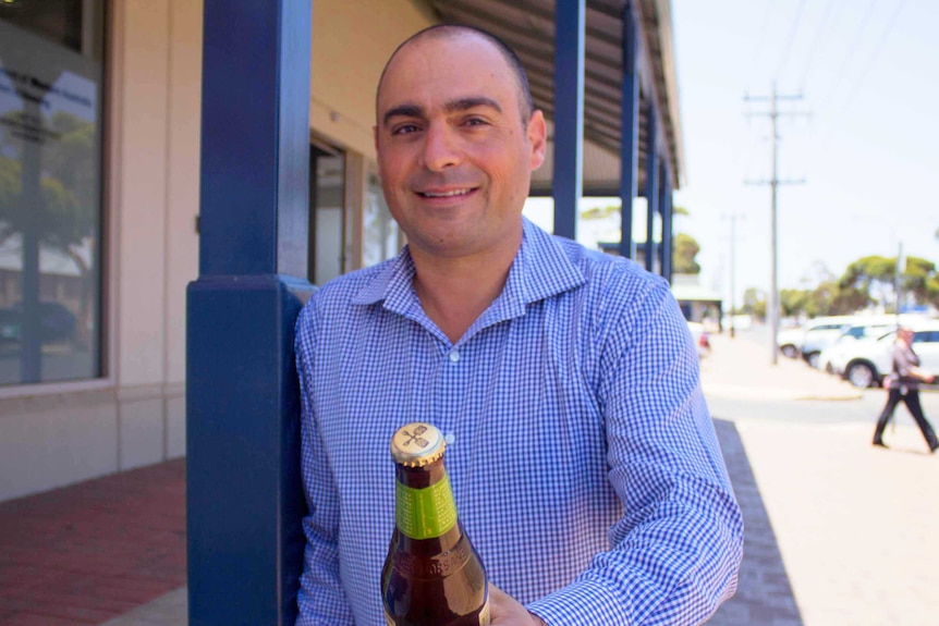 Kalgoorlie real estate agent Andrew Zafer holds a cold stubby of beer.