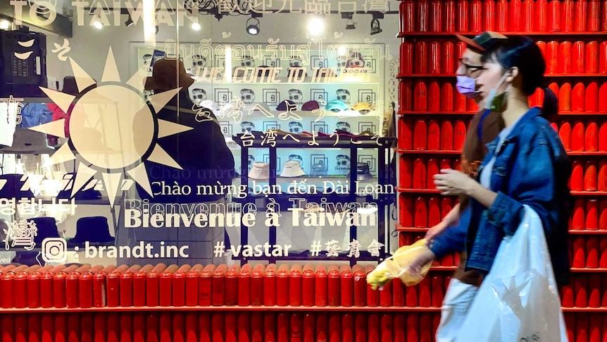 People stroll past a shop bearing a Taiwan flag