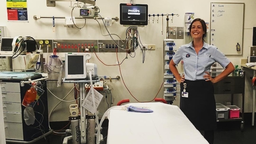 A nurse stands in a hospital room surrounded by machines