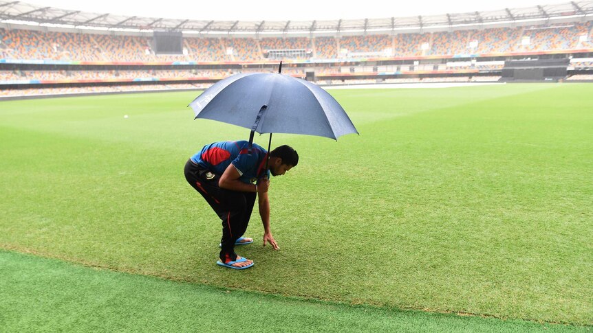 Bangladesh captain Mashrafe Mortaza checks the Gabba outfield as rain falls on February 20, 2015.