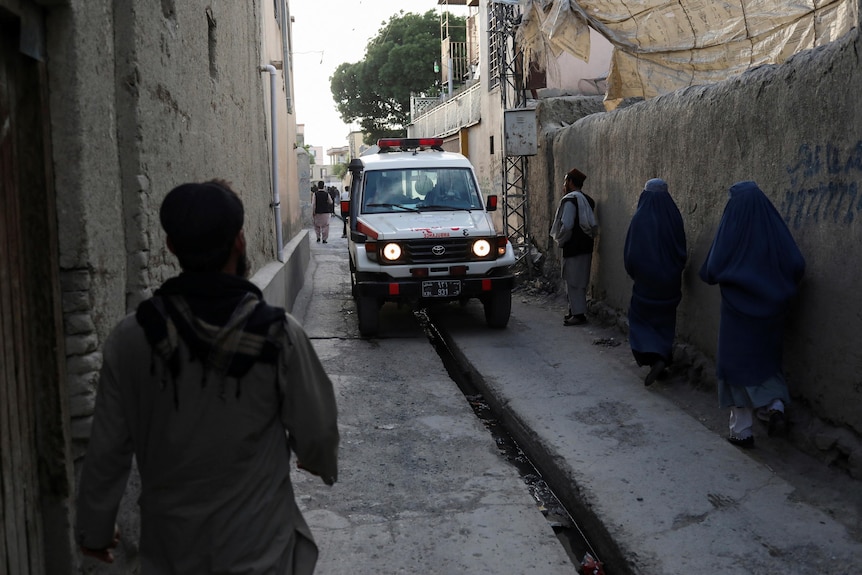 An ambulance driving along a narrow street.