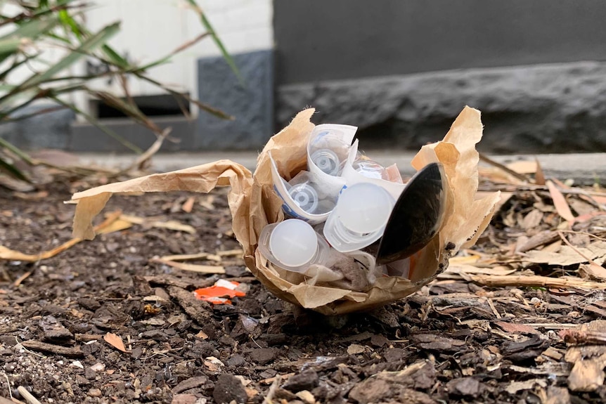 A paper bag on the ground in Richmond near the safe injecting centre, containing used syringes and a plastic spoon.