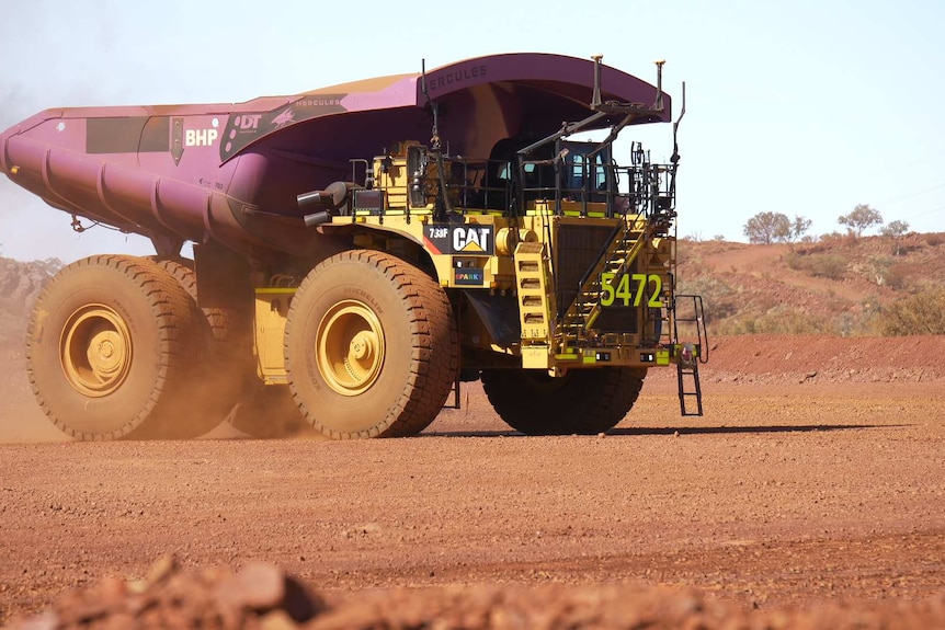 Mining truck with dust rising up around it.