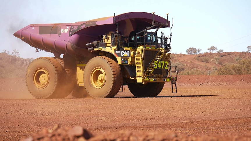 Mining truck with dust rising up around it.