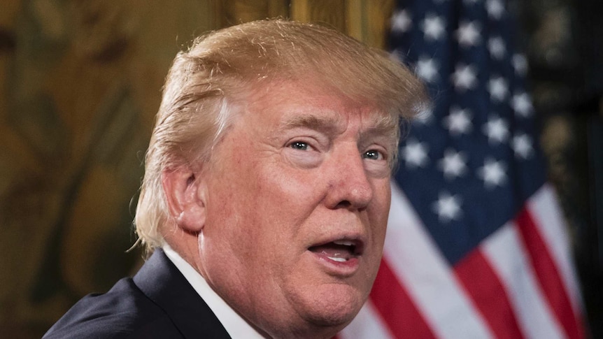 Tight shot of Donald Trump speaking with US flag behind him.