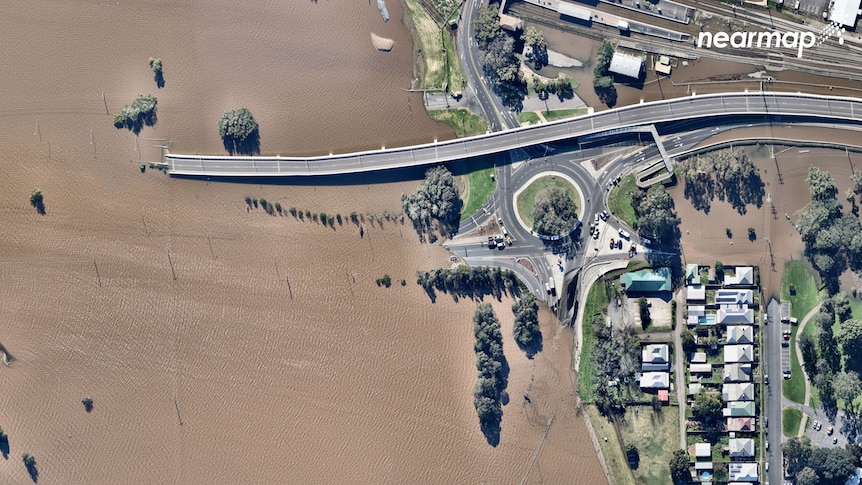Aerial image of a large roundabout and overpass leading into brown flood waters
