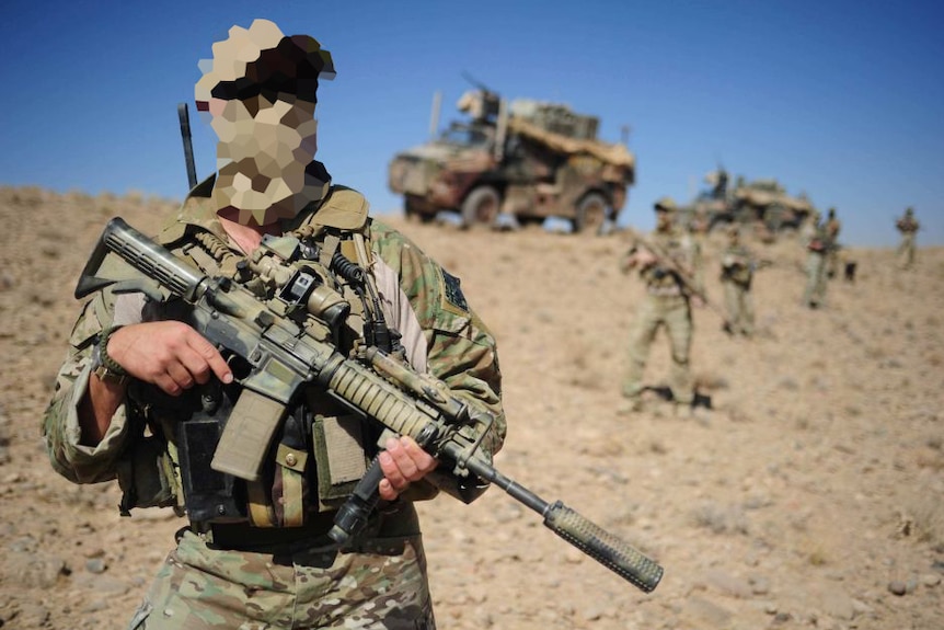 A soldier, whose face is pixelated, stands in camouflage gear with a firearm. In the distance behind him are trucks and troops.
