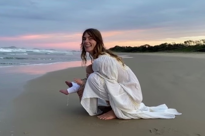 Montana holds her baby in at a beach in Byron Bay