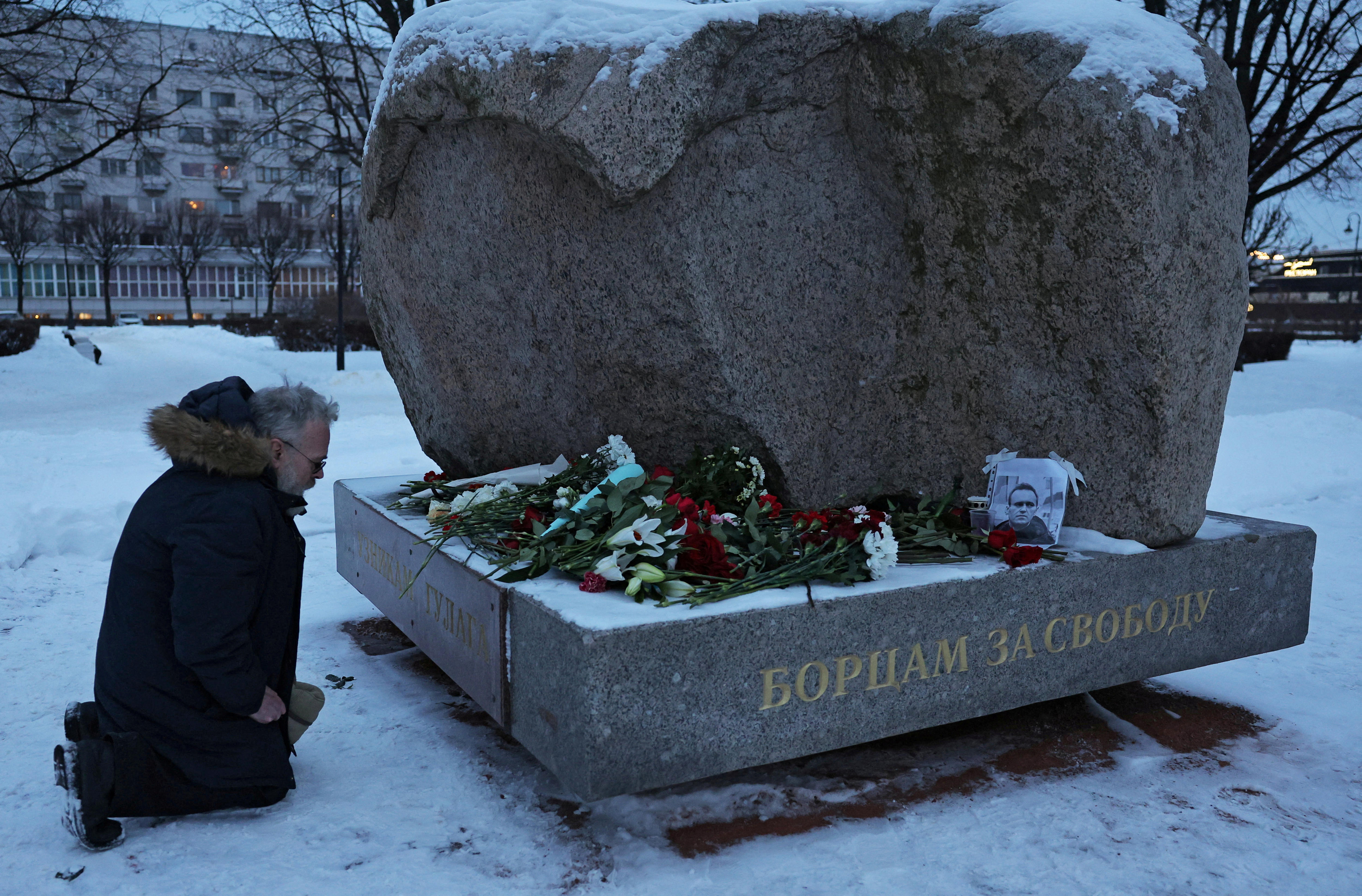 A man kneels at the monument to the victims of political repressions in St Petersburg following the death of Alexei Navalny.
