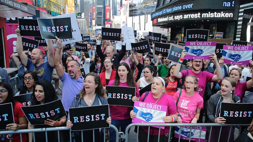 Protesters chant holding signs that read 'RESIST' and 'WE OBJECT' in Times Square, New York.