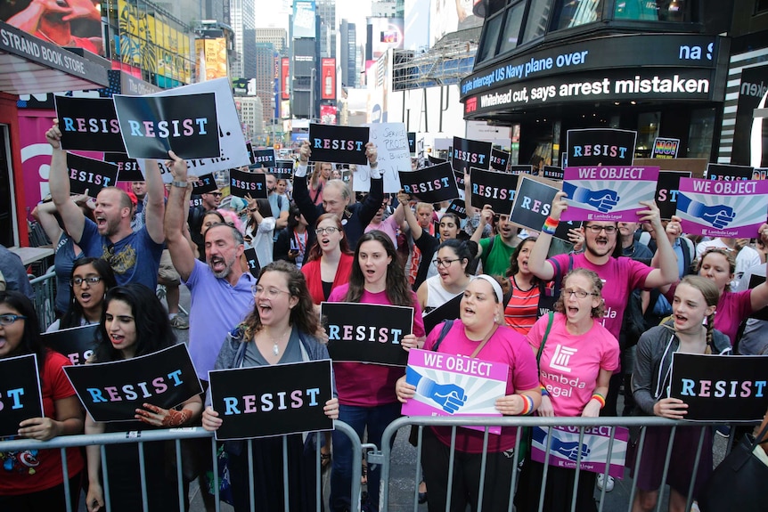 Protesters chant holding signs that read 'RESIST' and 'WE OBJECT' in Times Square, New York.