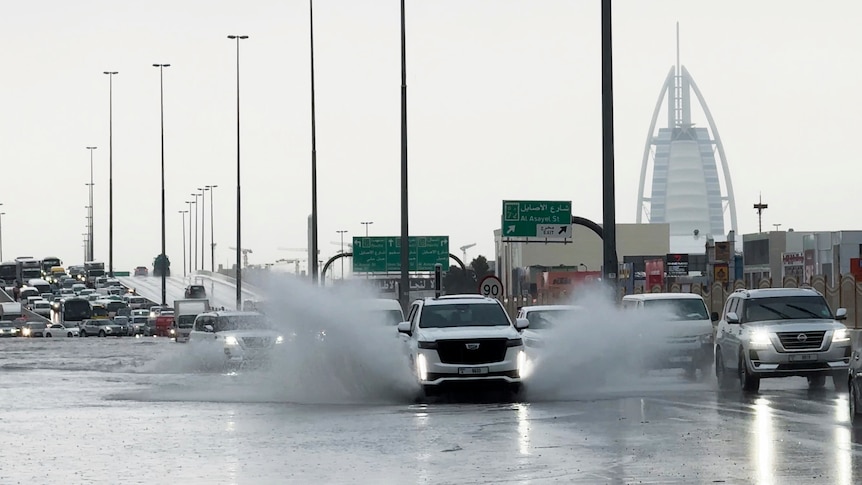 Cars driving through a wet road with water splashing from the wheels