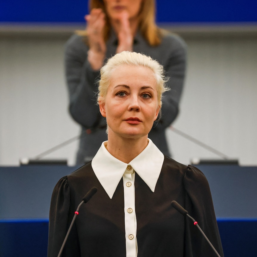 Yulia Navalnaya, a blonde woman, standing at a microphone. 