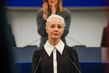 Yulia Navalnaya, a blonde woman, standing at a microphone. 