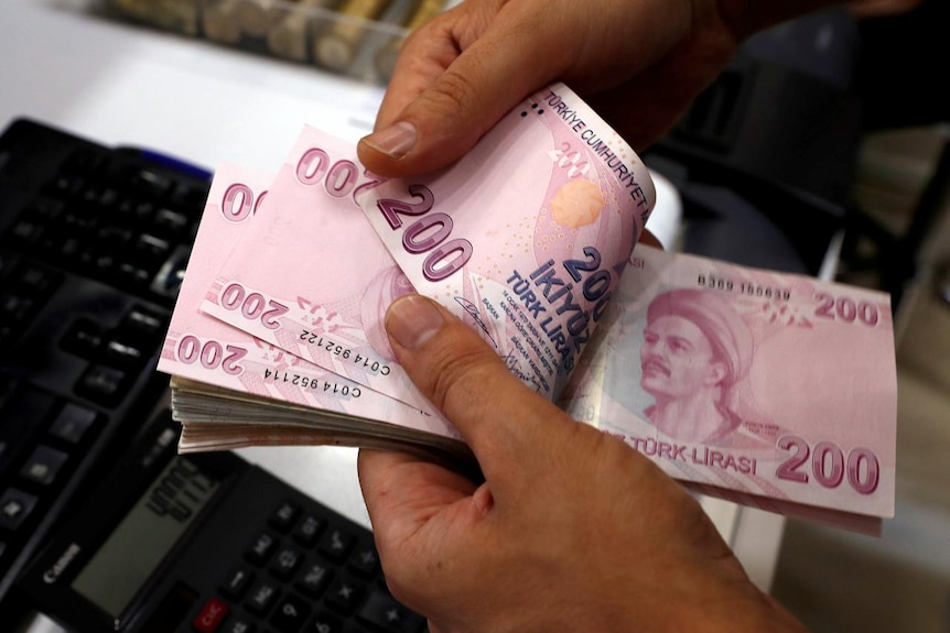 A money changer counts Turkish lira banknotes.