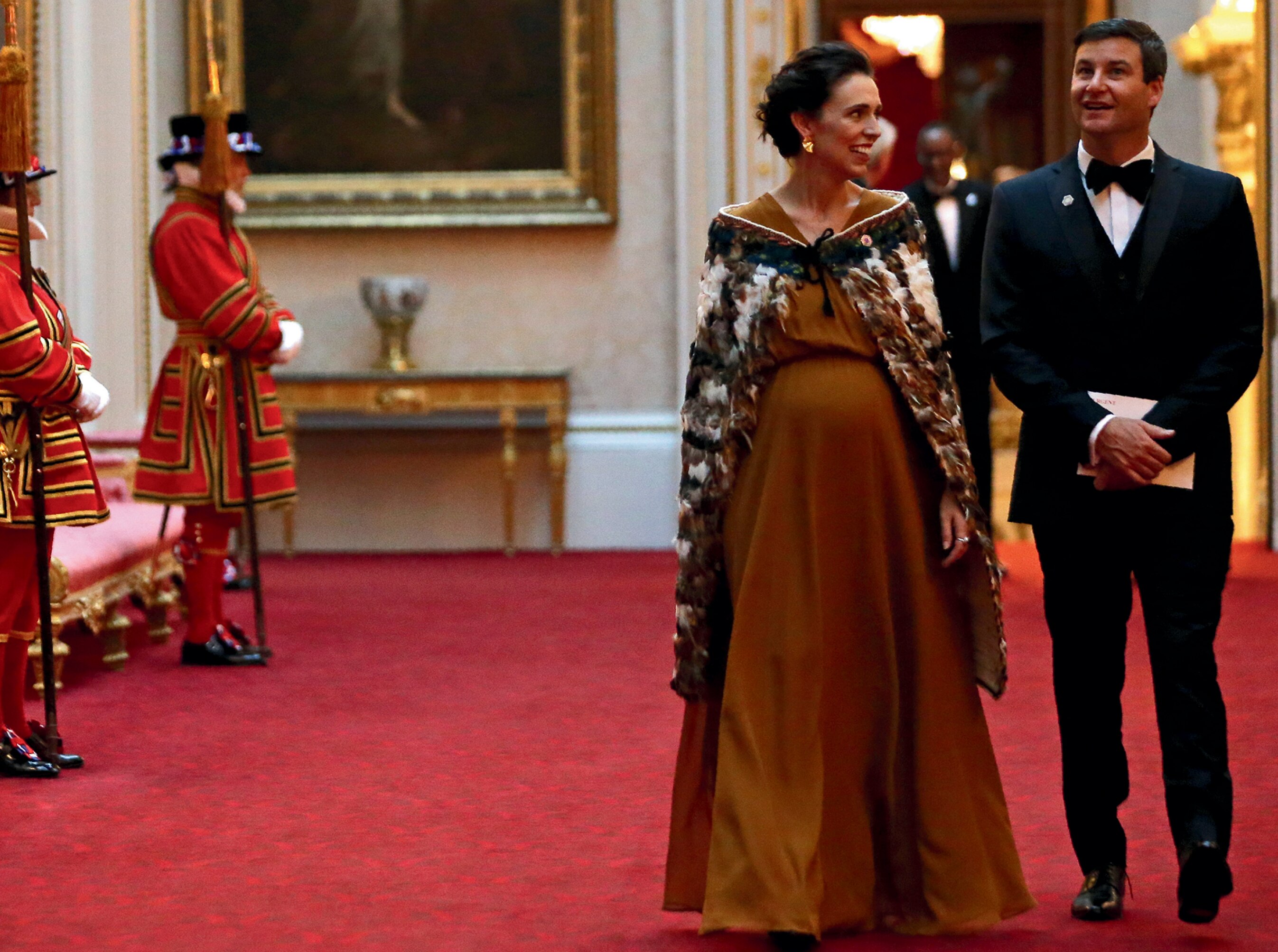 A woman and a man walk inside a palace.