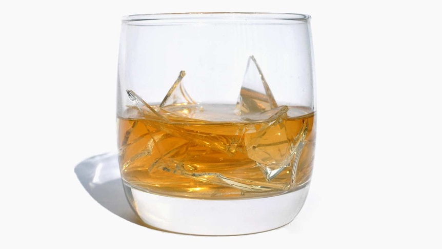 A whisky glass with broken glass in it.