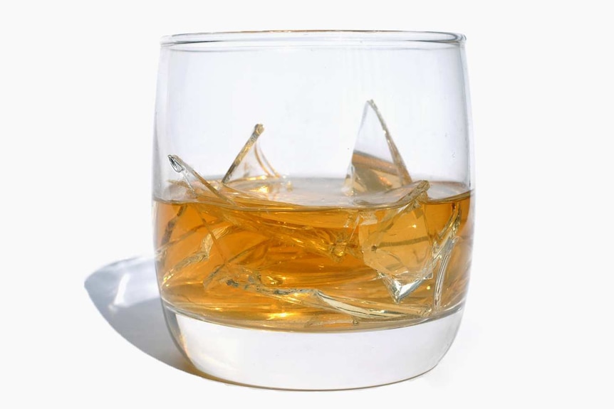 A whisky glass with broken glass in it.