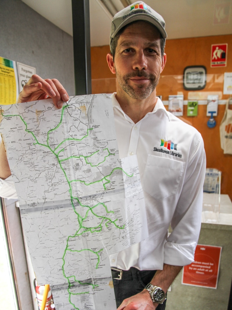 A man holds a long handmade map illustrating the bookmobile route.
