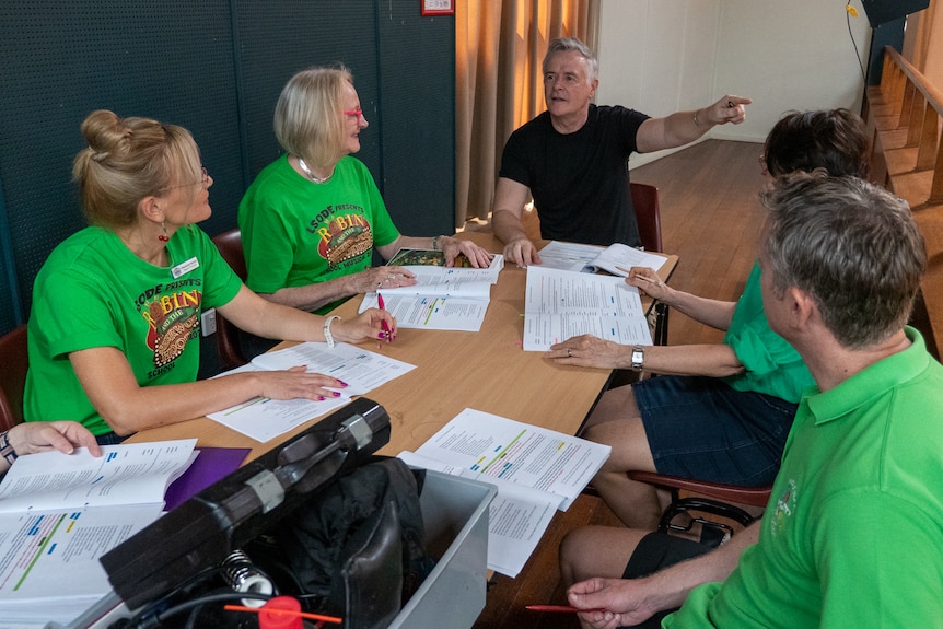 People sitting around a table looking at musical scripts, Longreach, November 2022.