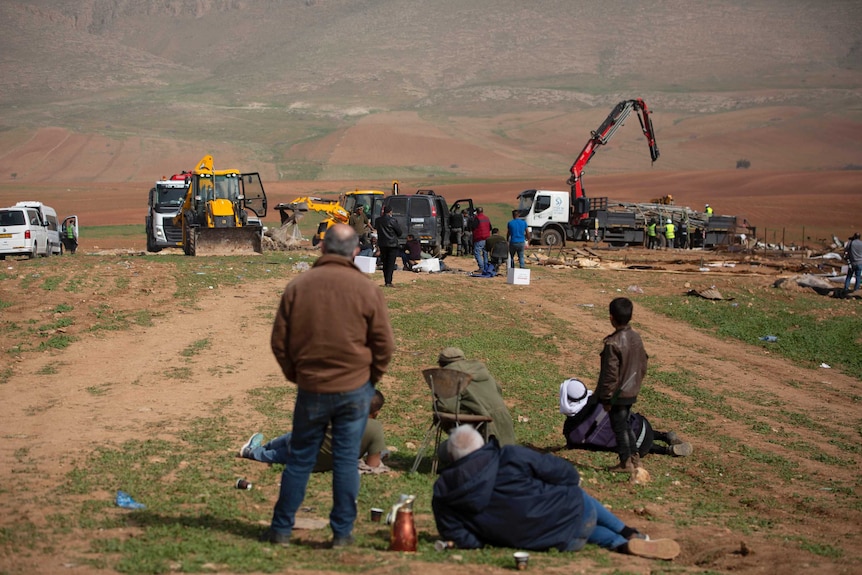 Palestinian Bedouin watch Israeli troops demolish tents and other structures