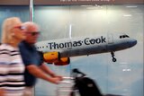 Passengers are seen at Mallorca Airport walking past a Thomas Cook sign after it collapsed.
