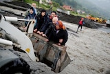 People are carried by a front loader as they evacuate from their flooded houses in Bosnia
