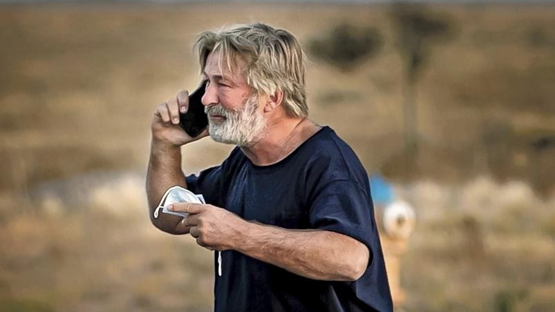 a man with grey-brown hair and beard makes a phone call in desolate dry countryside 