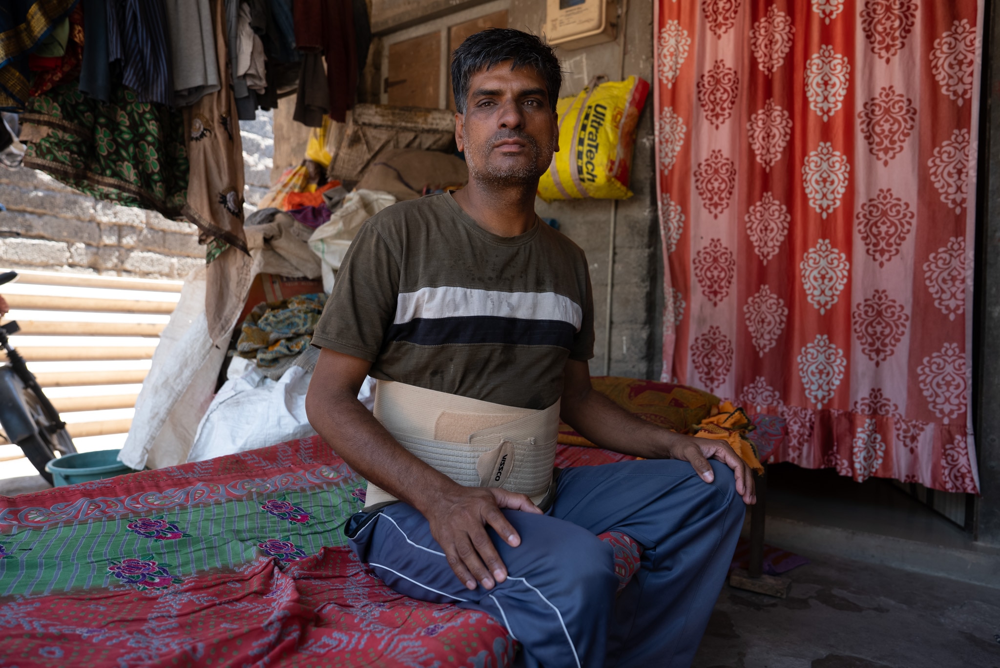 Hari Gupta, an Indian worker, sits on the floor with pillows.