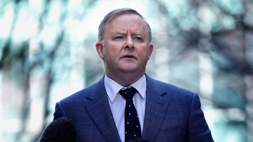 A man in a suit stands outside, it looks very cold.