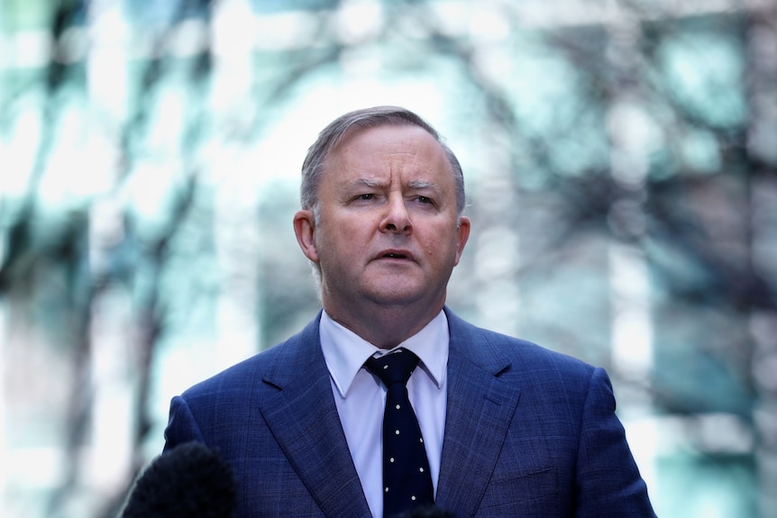 A man in a suit stands outside, it looks very cold.