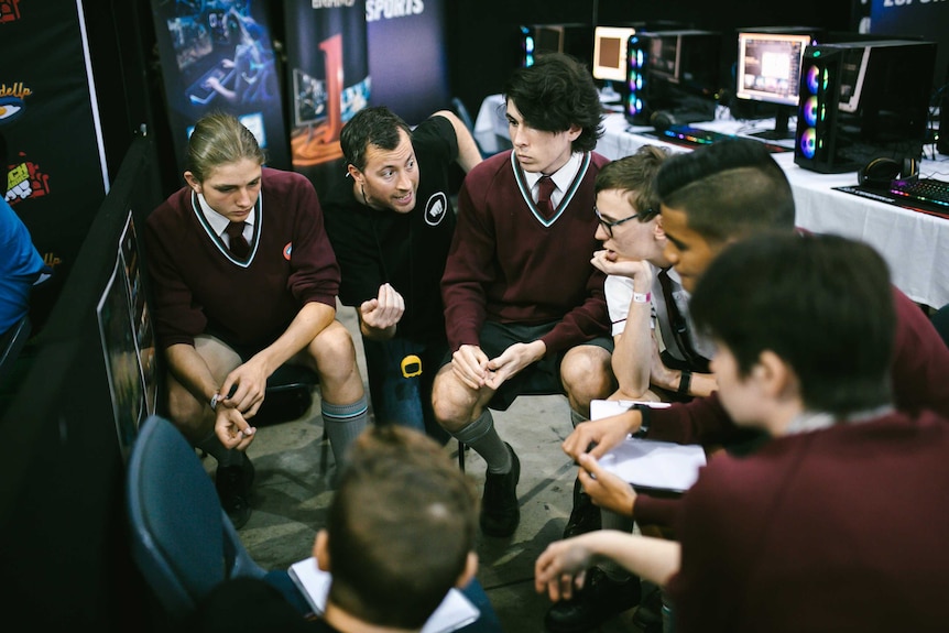 A group of teenagers sat in a circle receiving a pep talk