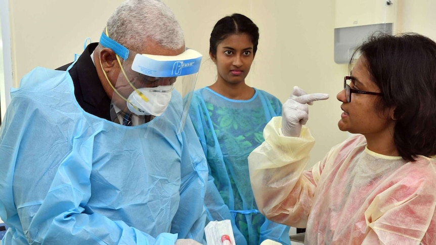 Frank Bainimarama wears personal protective gown, mask and visor as he visits a coronavirus testing lab.