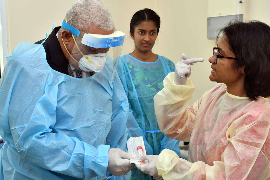 Frank Bainimarama wears personal protective gown, mask and visor as he visits a coronavirus testing lab.