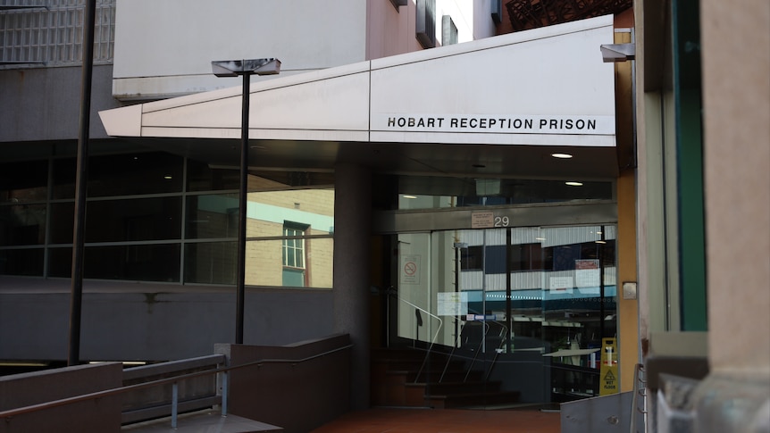 The front entrance of the Hobart Reception Prison, pictured are glass doors and a sign saying "Hobart Reception Prison"