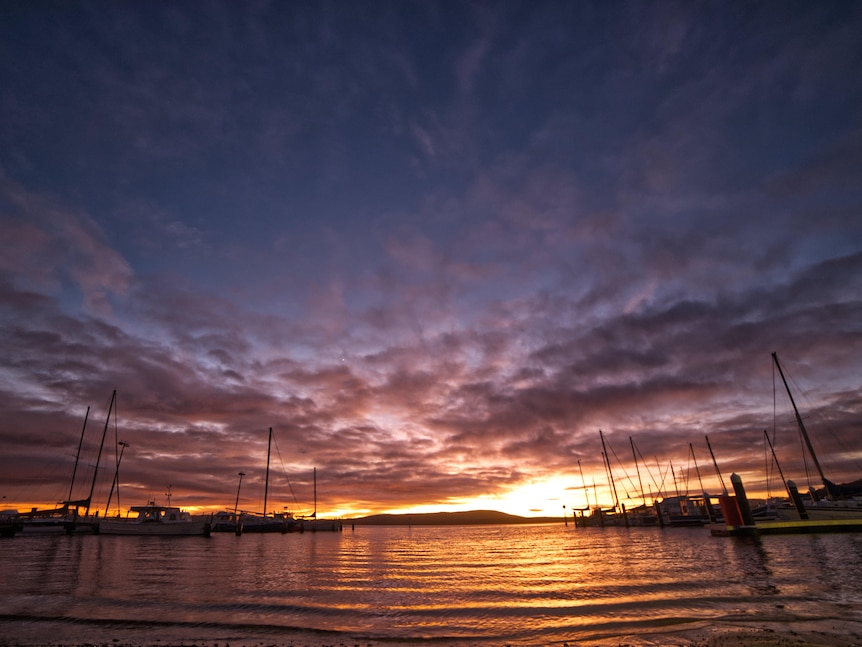 Orange hues in a sunset over the water with yachts
