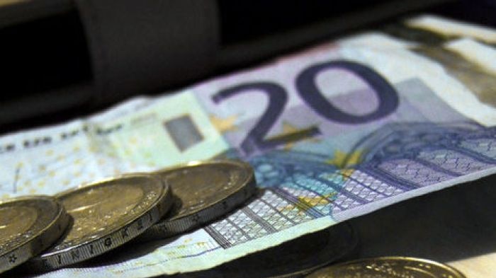 Euro currency notes and coins are spread on a desk