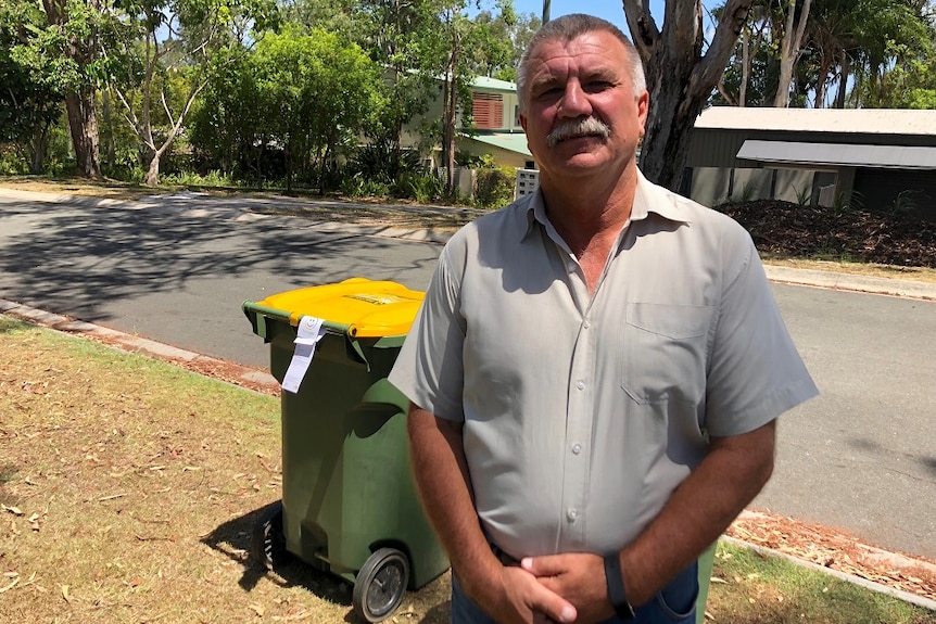 A man stands in front of a bin