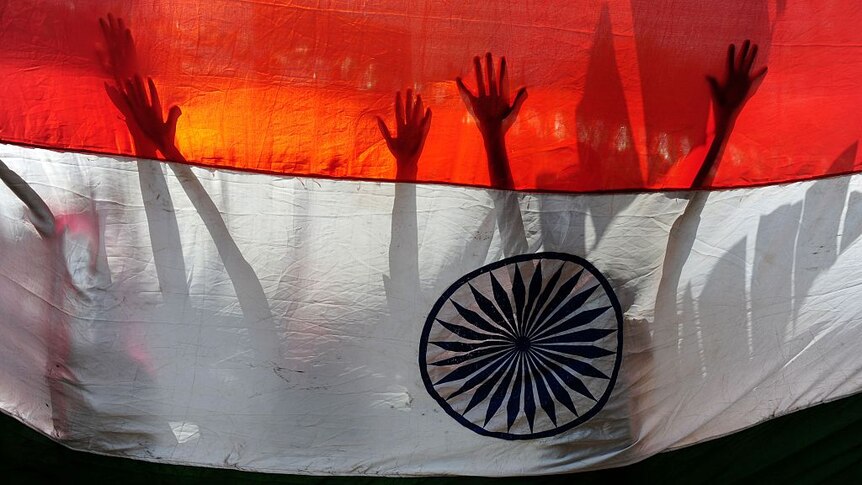 Silhouette of hands and arms behind Indian flag