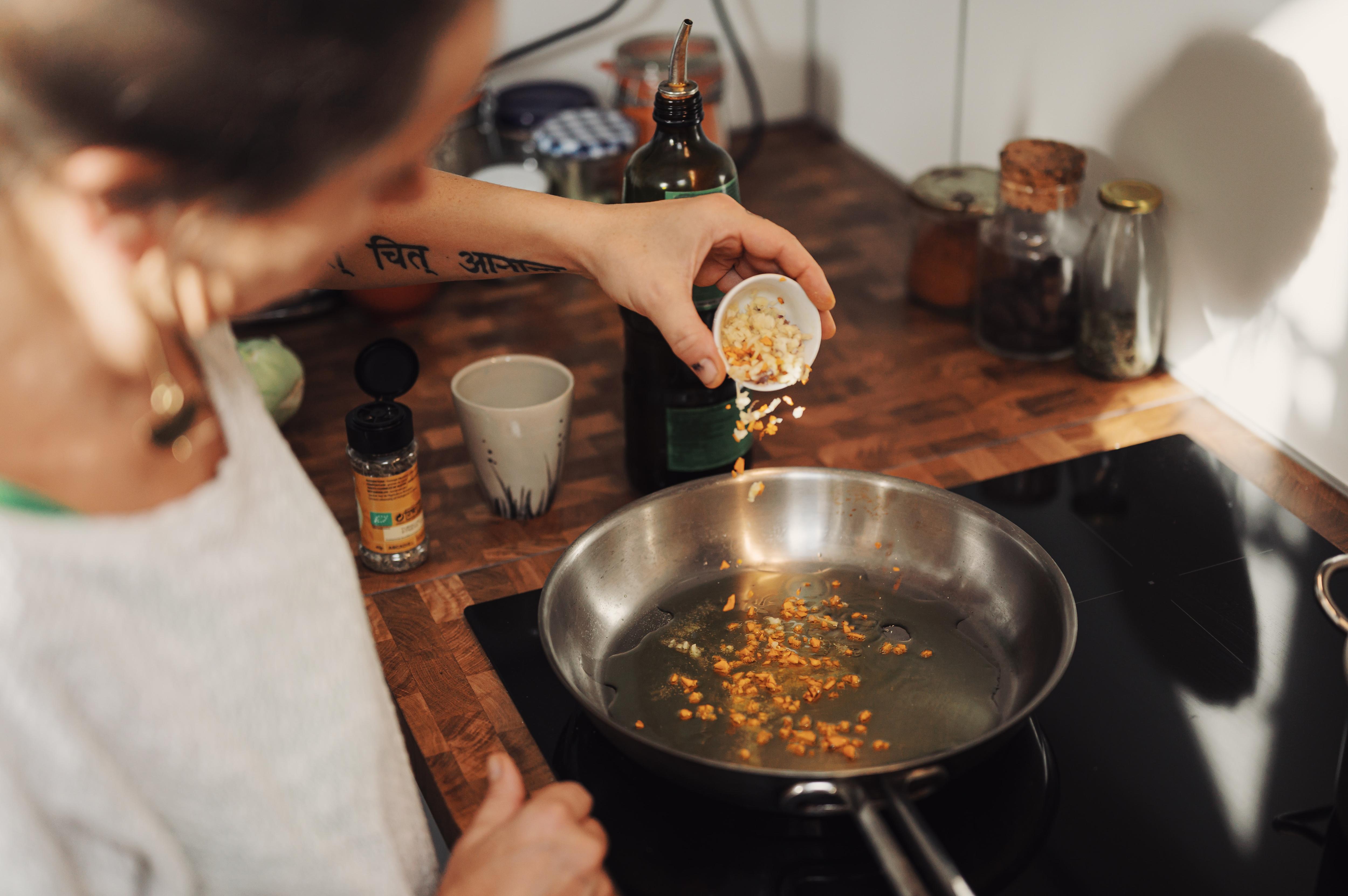 Photo from above a person's head as they pour seeds into a pan sitting on a flat, black induction cook top.