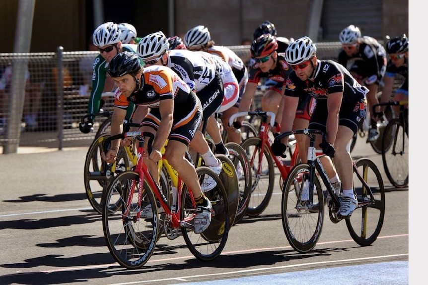 Ten cyclists wearing lycra jostle for first place in a velodrome race