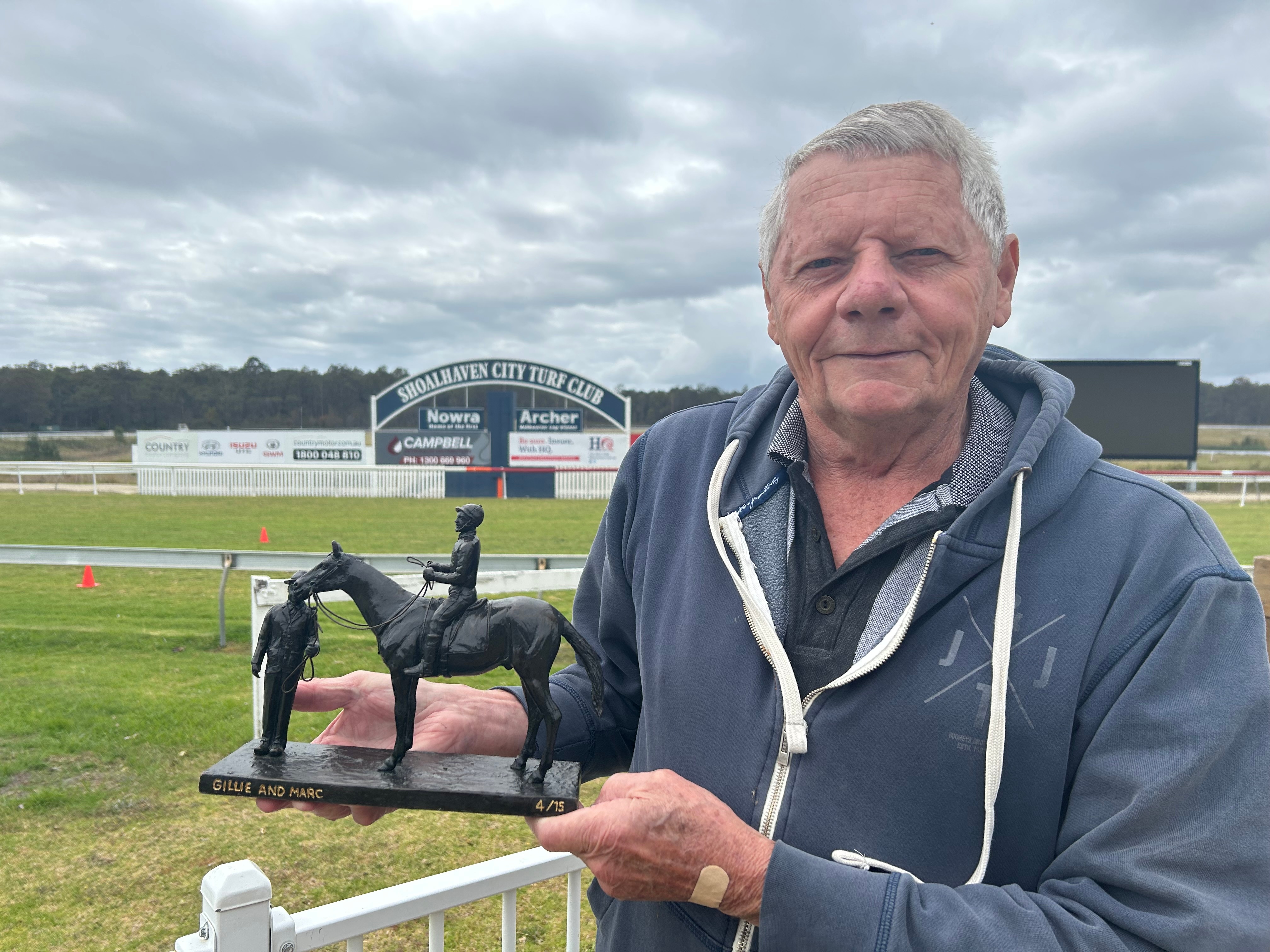 Man holds small sculpture at race track 
