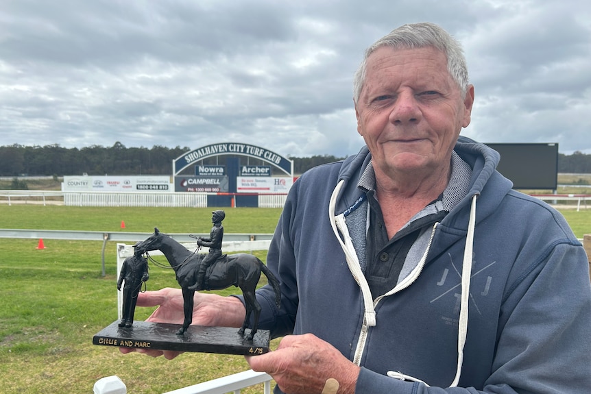 Man holds small sculpture at race track 
