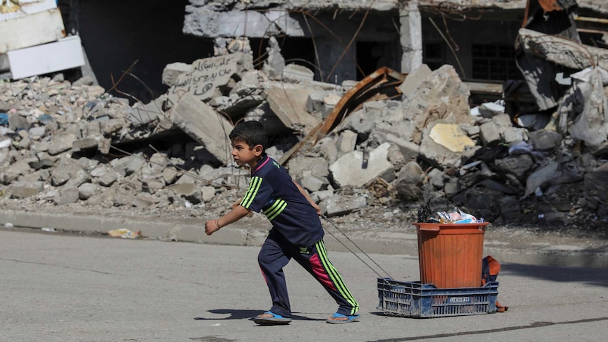 A boy pulls his belongings along a street in eastern Mosul