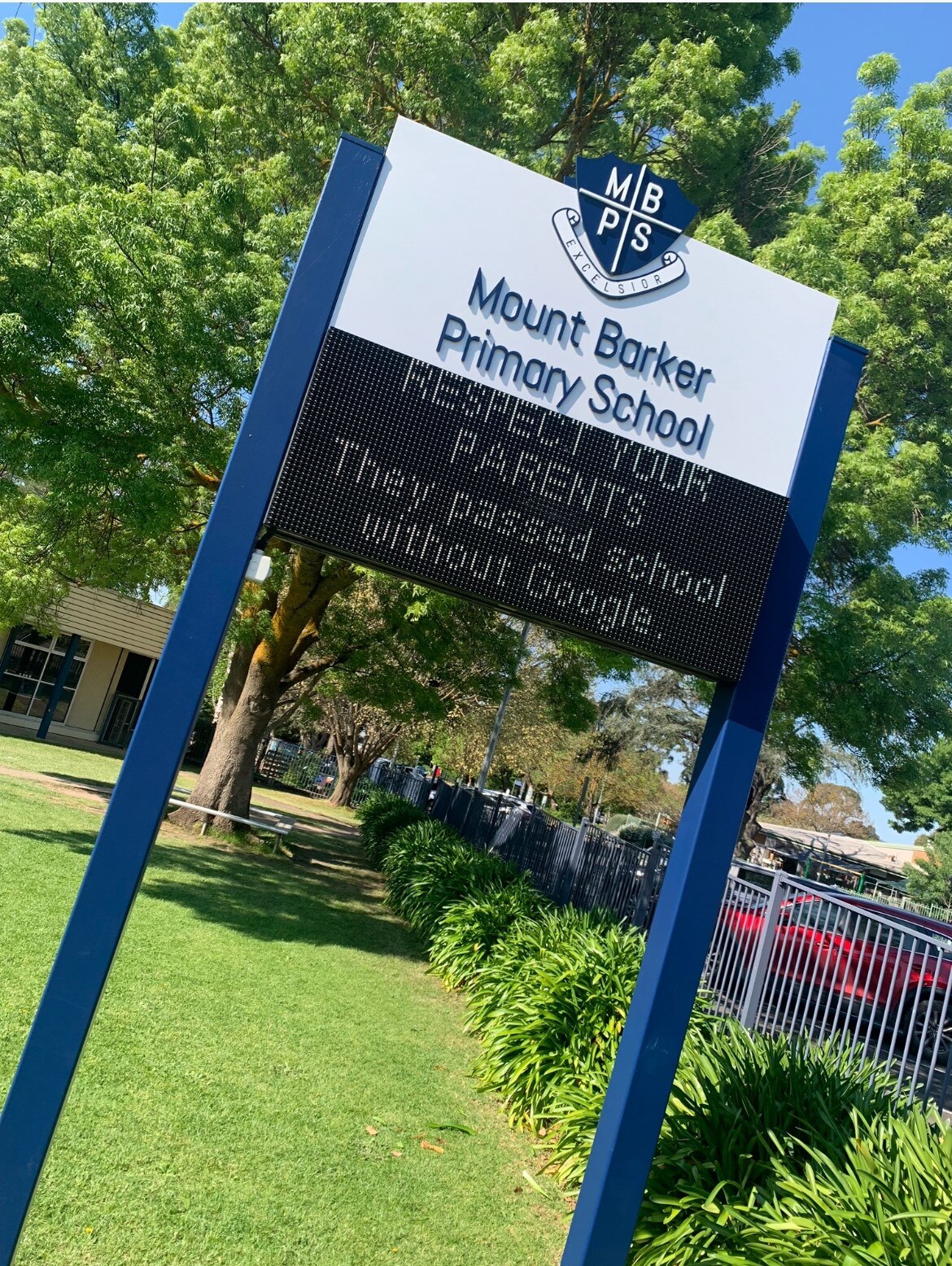 blue and white sign on two long legs with logoi at top and LED screen a bottom