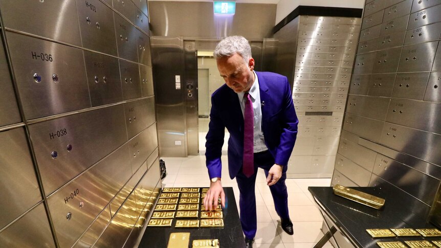 A man inspects gold bars inside a vault.