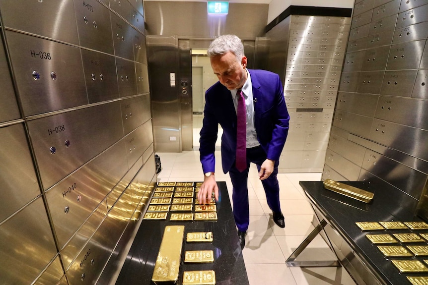 A man inspects gold bars inside a vault.